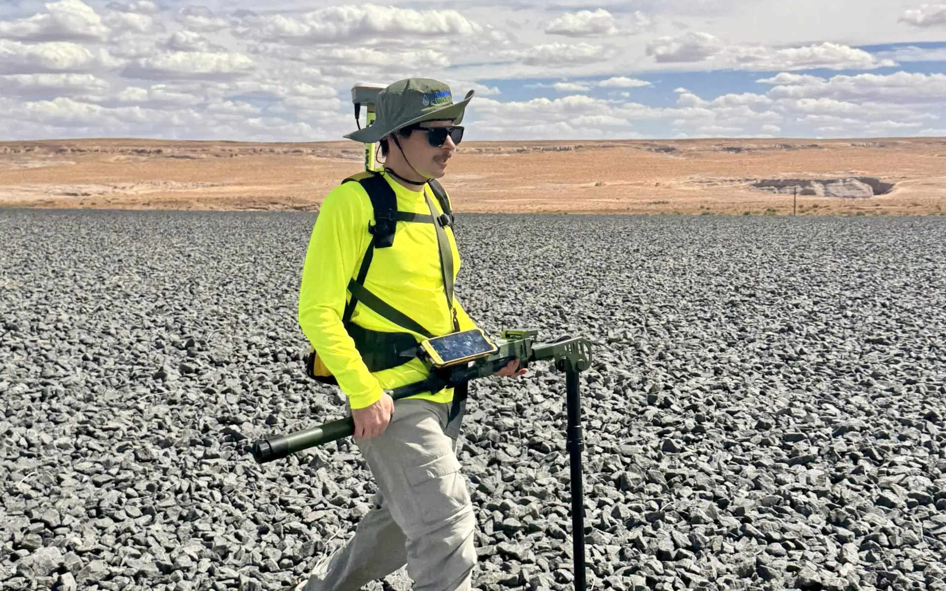 Drummond Carpenter field technician carrying GPS survey equipment across the rock-armored cover of a disposal site near Tuba City, Arizona.