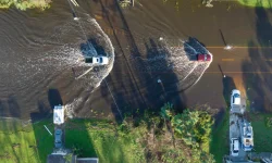 Flooded Florida road with evacuating cars and surrounded with water houses in suburban residential area. Consequences of hurricane natural disaster.